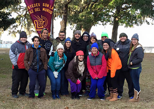 With their iconic burgundy banner displaying the right arm of Christ, and the message "You are the light of the world," Encuentros Juveniles members posed for a group photo while leading the first Encuentro in Alabama. In the photo, (back row, from left) are Marcos Mirabent, Robert Barcia, Alexander Gomez, Mark Gomez, Gabriel Aguilera, CJ Cristobal, Peter Fleitas, and Hector Daniel Ponte. In the front row, from left, are Gaby Gordillo, Zoila Murgado, Rebecca Garcia, Vicky Cheena Martinez, Eli Martinez and Carolina Hernandez.