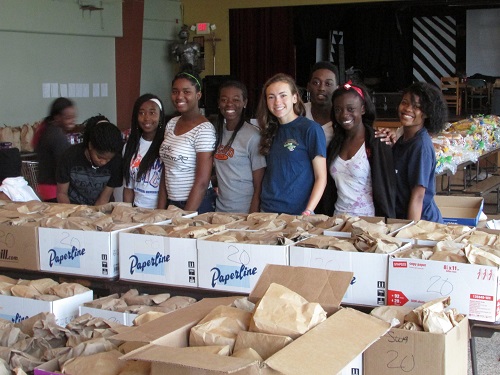 Archbishop Curley Notre Dame students pose with some of the record-breaking 4,000 lunches they prepared for the poor. From left: Naika Imbert, grade 12, Tracey Dominique, grade 11,  Danielle Antoine, grade 11, Ashley Savain, grade 11, Rhian Romanik, grade 12, Nickolas Moss, grade 12, and Maniola Mompremier, grade 11.