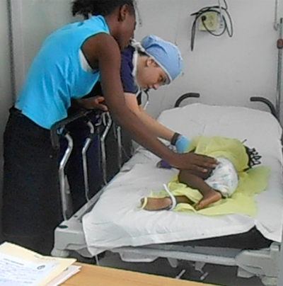 Alexandra "Lexi" Thaller (center) checks on a young patient as a parent soothes her child. Lexi, a junior at St. Brendan, accompanied her father  Dr. Seth Thaller and a team of UM/Jackson Hospital doctors to Port-Au-Prince, Haiti for Project Medishare.