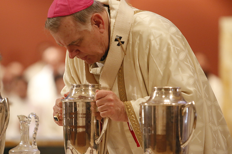 Archbishop Thomas Wenski blows into the oil of chrism, consecrating it for use in baptisms and confirmations and the consecration of churches and bishops.