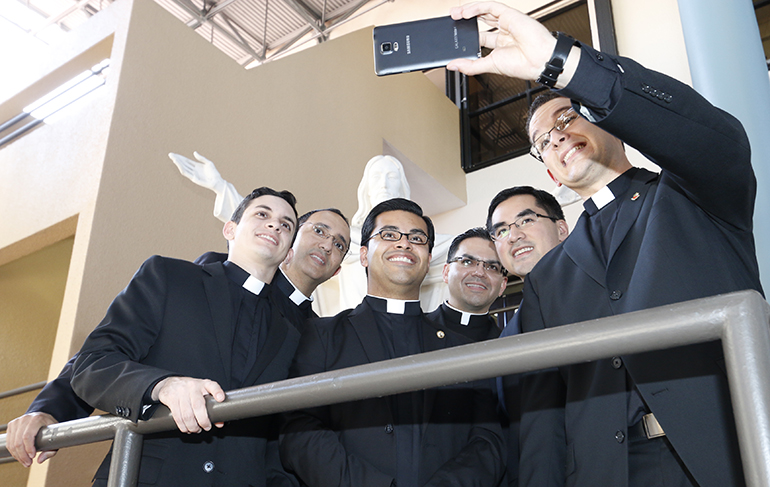 Los miembros de la ordenación 2015 se toman un selfie (auto fotografía) en el atrio del Centro Pastoral de la Arquidiócesis, a pocas semanas de su ordenación. De izquierda a derecha: Los diáconos Michael García, Julio De Jesús, Yamil Miranda, Javier Barreto, Phillip Tran y Bryan García, sosteniendo el teléfono celular.