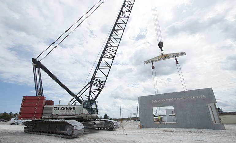 A crane lifts a pre-cast concrete wall to create the outer structure of Our Lady of Guadalupe's San Juan Diego Parish Center. The construction method is known as tilt-up and it is the most cost-effecitve method when a building's walls reach beyond a certain height.