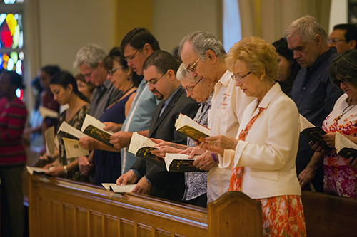 Neophyte Catholics and their families and friends pray during Mass