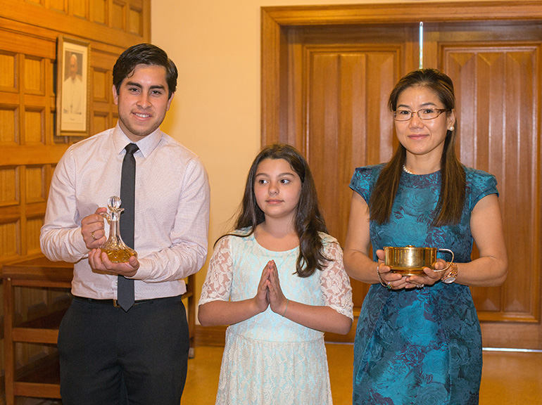 Neophyte Catholics Pierre Barrera, Alexiane Jimenez, 10, and Berardelli Rojas prepare to bring the offertory gifts to Archbishop Thomas Wenski.