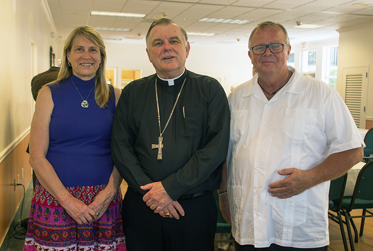 Archbishop Thomas Wenski poses for a photo with neophyte Michael Preston and his wife, Lucy, at the reception after Mass.