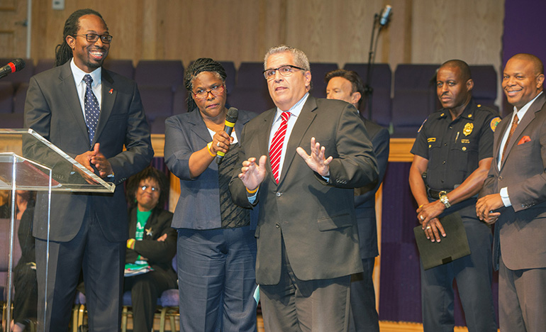 Miami-Dade Public Defender Carlos Martinez speaks about youth arrests as Dr. Inaki Bent, of St. Mary Cathedral, looks on and Regina Johnson holds the microphone.