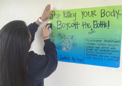 A St. Thomas Aquinas student puts up a poster for "Earth Week." Facts about disposable plastics, especially disposable water bottles, were posted around the school. The school also screened the film "The Story of Bottled Water" at the beginning of science classes on Earth Day.