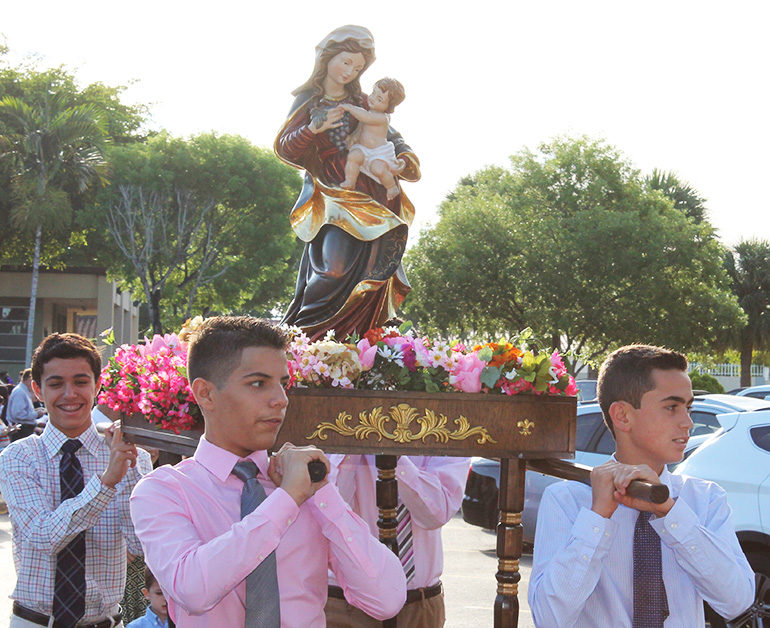 Older boys carry the image of Mary from the school to the church during the May crowning at St. Kevin School.