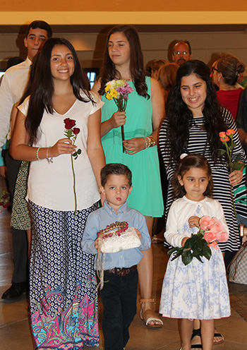 The oldest and youngest students at St. Kevin School take up the crown and flowers during the May 1 crowning of an image of Mary.