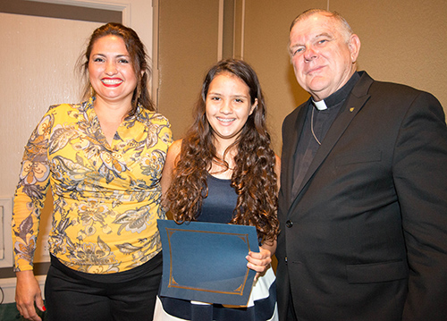 Archbishop Thomas Wenski poses with $ 5,000 scholarship recipient Christodoula Shiahinian, of All Saints School in Sunrise, and her mom, Sandra Coello.