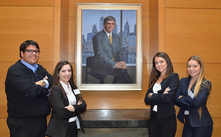 Members of Archbishop Edward A. McCarthy High School's Business & Finance Team pose in front of a portrait of  Patrick T. Harker, dean of the Wharton School of Business 2001 to 2007, who in addition to many other accomplishments accumulated more than  million in research grants. From left: seniors Gabriel Tejada, Marissa Salaya and Claudia Teresa-Calleja and junior Lara Suarez.