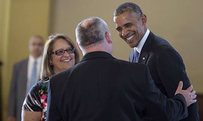 Cristina Brito, secretary at the National Shrine of Our Lady of Charity, serves as an interpreter as her boss, Father Juan Rumin Dominguez,  welcomes President Barack Obama to the icon for Miami's Cuban exile community.