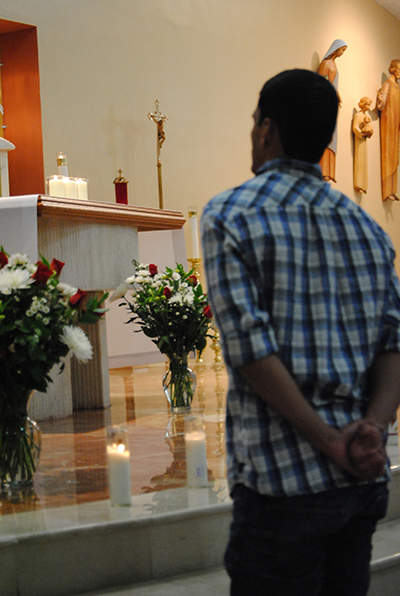 David Toribio, from St. Augustine Young Adult Group, prays after placing a candle at the sanctuary of St. Kieran Church during the first archdiocesan Young Adult Ministry event.
