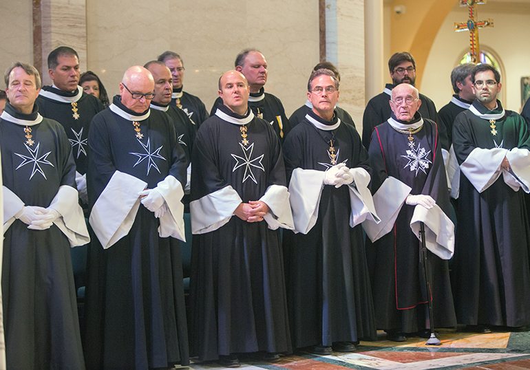 Knights and Dames of Malta sit in the sanctuary as Archbishop Thomas Wenski celebrates the Mass.