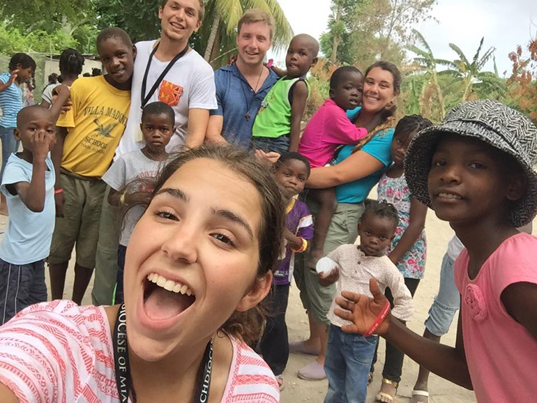 Christy Piña (front), Joaquin Pannunzio, Jonas Erthal and Brittani Garcia (back, from left) pose for a selfie with campers in MÃ´le St. Nicolas, Haiti.