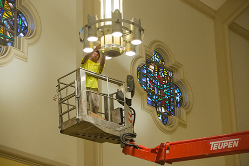Workman Mauricio Cortez changes lightbulbs in St. Mary Cathedral standing inside a basket on the Teupen Leo series aerial lift.