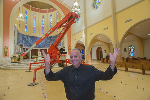 Ruben Jimenez, business operations manager for St. Mary Cathedral and school, stands in front of the spider-like machine from which workers touched up the cathedral's five-story high ceiling and changed out the chandelier lights.