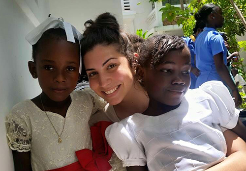 Carolina Ulloa, a young adult from St. Augustine Church and Catholic student center, hangs out with children from Pte. Rivière-de-Nippes, in the Diocese of Anse-a-Veau, after Sunday Mass. "God allowed me to see and experience what truly breaks his heart through serving those in need," she said of her mission experience. "(These) beautiful smiles will be with me forever."