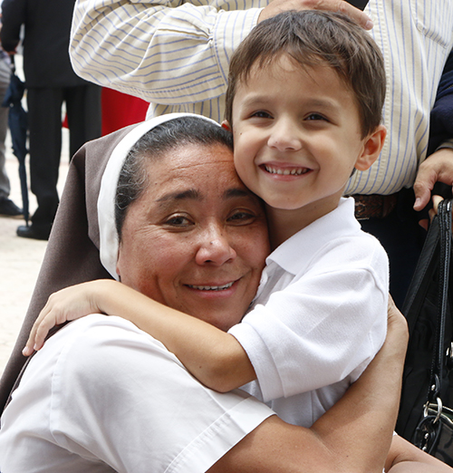 La Hna. Martha Gómez-Chow de Las Siervas de los Corazones Traspasados de Jesús y María, recibe un abrazo de un joven amigo después de la Misa por el 25 aniversario.