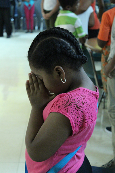 A St. Helen School student is deep in prayer as she thanks God for all of the blessings she has received in the form of back-to-school supplies. St. Helen School was one of eight schools who received supplies donated by the Archdiocese of Miami.