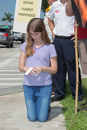 Camilla Griffith, 13, prays during the protest.