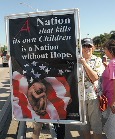 Joan Crown, director of the archdiocesan Respect Life Office, holds up her sign.