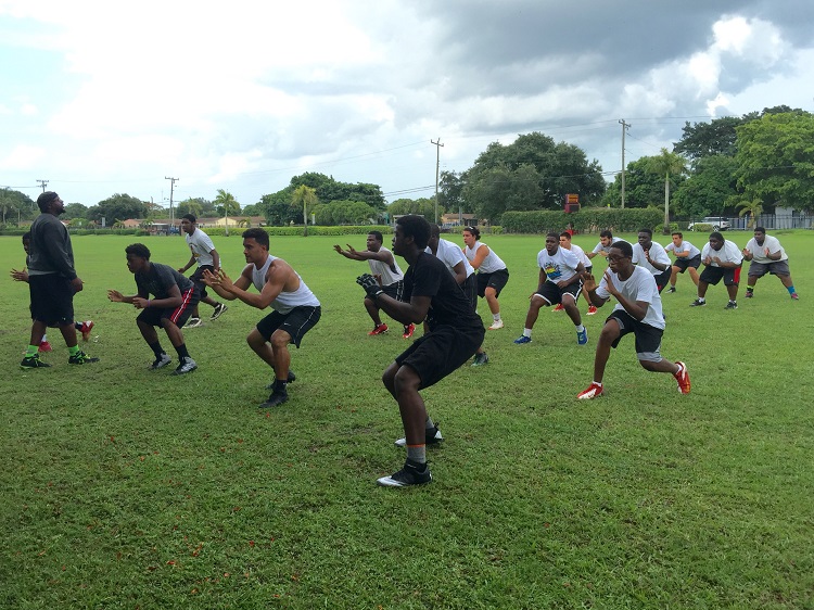 Members of the Msgr. Pace High Spartan football team get instructions from John Roll, Pace's defensive line coach, during pre-season conditioning.