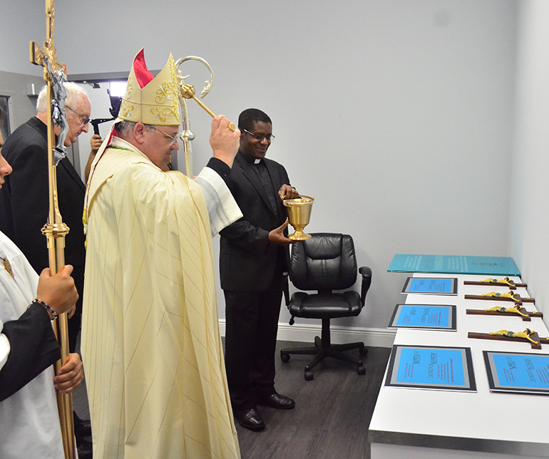 Auxiliary Bishop Peter Baldacchino blesses the crucifixes and mission statements which were later hung throughout the new locker room.