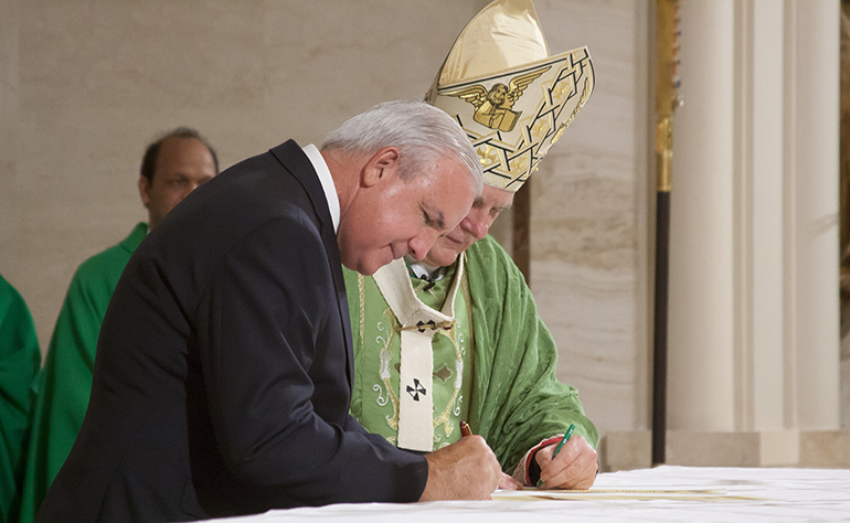 Archbishop Thomas Wenski and Carlos A Gimenez, mayor of Miami-Dade, sign the declaration officially consecrating Miami-Dade County.