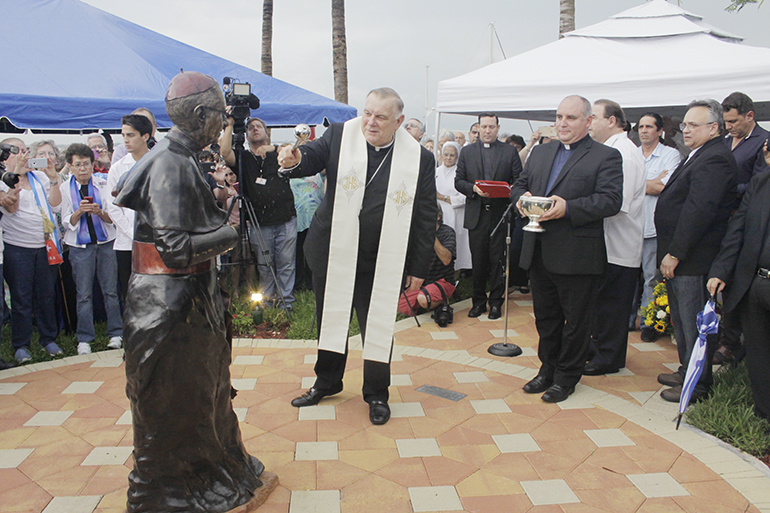 Archbishop Thomas Wenski blesses Bishop Agustin Roman’s statue newly unveiled, with him Father Juan Rumin Dominguez, rector of the Shrine.
