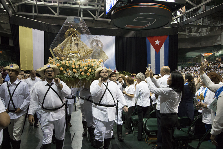 Vestidos de "mambises", miembros de Encuentros Juveniles cargan la imagen de la Virgen de la Caridad en procesión por el Bank United Center antes de la Misa.