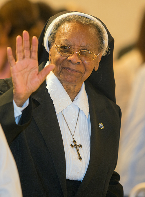 Sister Clementina Givens waves at other religious during the sign of peace.