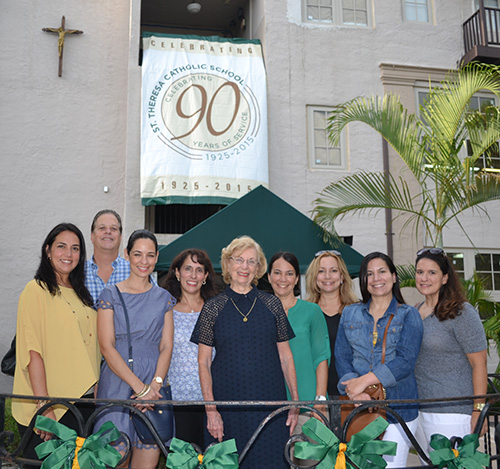 Posing under the anniversary banner, from left, are St. Theresa School alumni whose children and/or grandchildren now attend the school: Vivan Ros Varela, Class of '84, Miguel Lanz, Class of '80, Vanessa Rodriguez, Class of '87, Silvia Gonzalez Esposito, Class of '77, Louise Fitzgibbon Bennett, Class of '46, Anetxu Calonge, Class of '88, Michelle Garcia Rivera, Class of '86, Maite Rezola Herreria, Class of '90, and Elena Sanchez Galarrage, Class of '88.