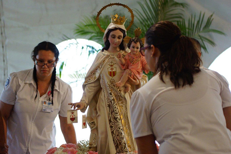 Mercy Hospital nursing students carry the image of Our Lady of Mercy in procession at the start of the Mass.