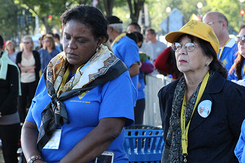 Pilgrims Margaret Noailles (left) and Ann Tan (right) take a moment to reflect while watching the canonization Mass of Junipero Serra on a large screen in the National Mall.