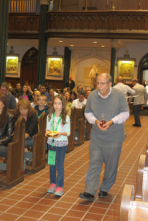 Dr. Santiago Cardenas and his 7-year-old granddaughter, Farah Pina, take up the offertory during the Mass the Miami pilgrims celebrated with Archbishop Thomas Wenski in Philadelphia.