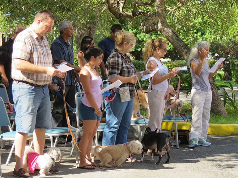 Pet owners read a prayer, along with their furry companions, before the blessing of the animals, held outside of St. Martha Parish Hall.