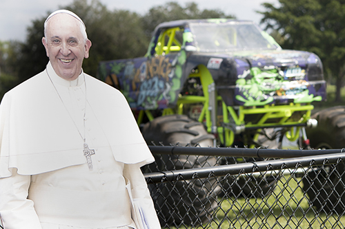 The Pope Francis cutout seems to be enjoying the Kid Monster Trucks behind him.