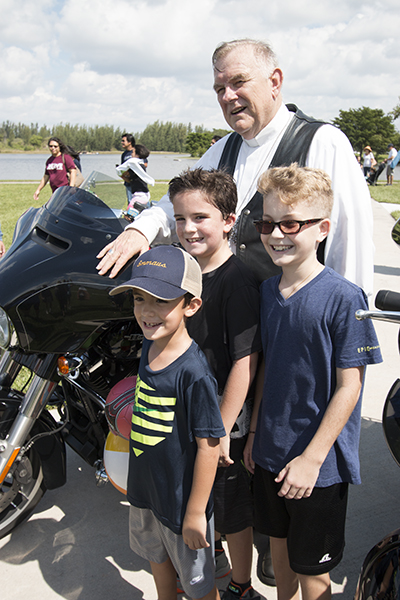 After Mass, Archbishop Thomas Wenski spent a long time posing for photographs, often with his Harley-Davidson. Here he takes a photo with Joey Pfeiffer, front, his brother Billy and their friend, Noah Rodriguez of St. Mark Parish in Southwest Ranches.