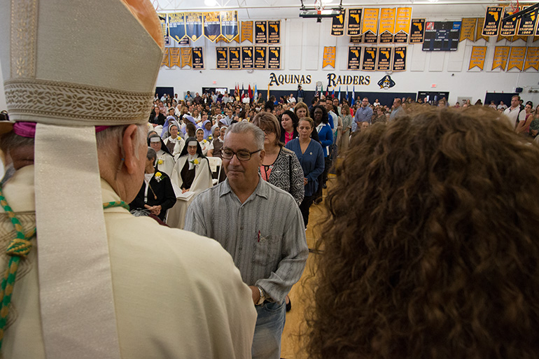 Archbishop Thomas Wenski hands out diplomas to catechists who have completed their certification coursework.