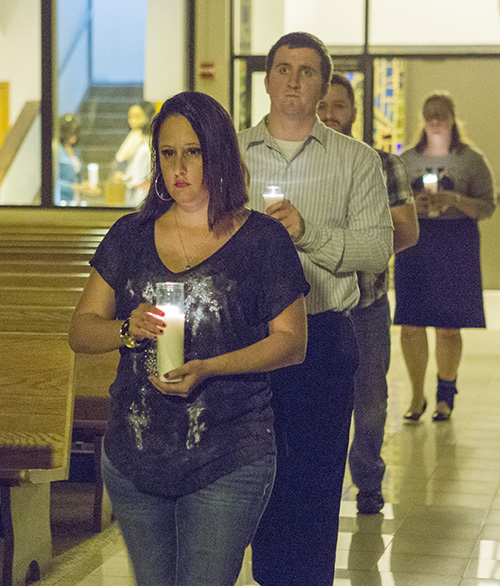Young adults carry candles to the altar after Mass.