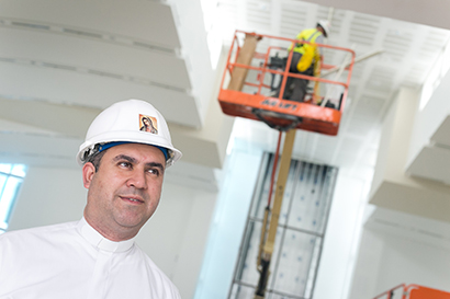 Father Israel Mago, pastor of Our Lady of Guadalupe Church in Doral, stands in its interior, where workmen are rushing to finish by the Dec. 12 dedication date.