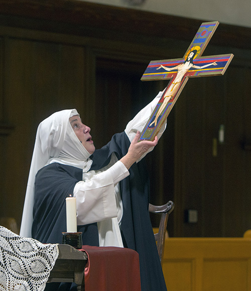 Dominican Sister Nancy Murray holds up a crucifix during her animated one-woman show portraying St. Catherine of Siena.