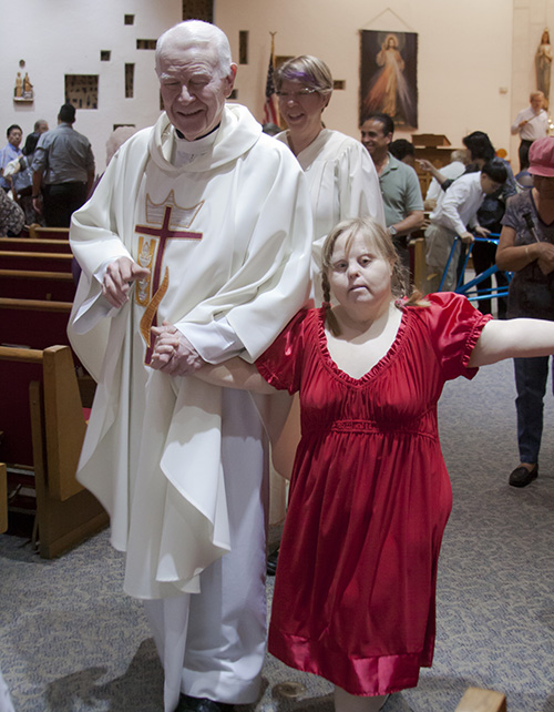 Kathleen Searless, parishioner at St. Malachy Church in Tamarac, processes out of church holding the hand of her pastor, Father Dominick O'Dwyer, after the second annual White Mass in Broward County.