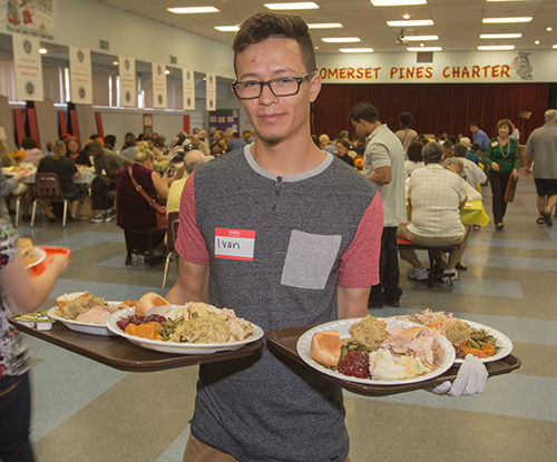 Volunteer Ivan Araiza carries food to diners at the tables.