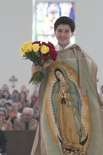 Diego Planos, 13, impersonating St. Juan Diego, open his "tilma" and drops flowers on the sanctuary. His family is from Mexico but have been members of Our Lady of Guadalupe Church since he was born.