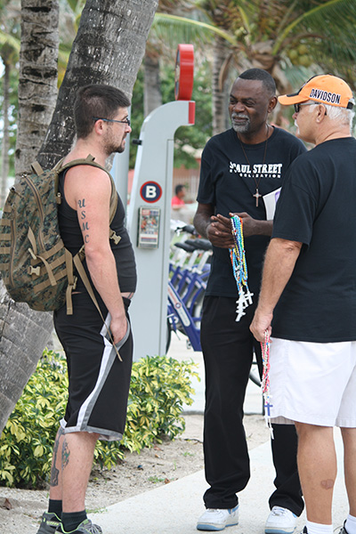 After capturing the attention of a young pedestrian (left), St. Paul Street Evangelization members Josue Dumercy (center) and Bill Amos witness to the Catholic faith.