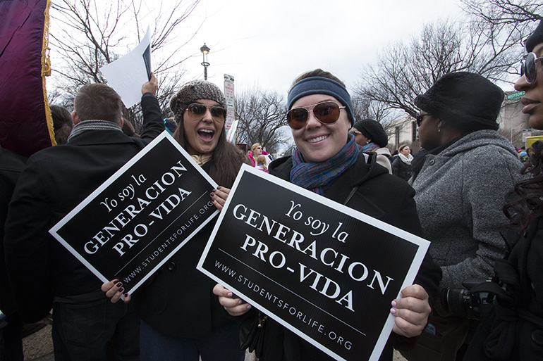 Christina Lujan, left, and Brittani Garcia of Immaculate Conception's Ablaze youth group, hold up their pro-life signs during the 2015 March for Life in Washington, D.C. Young adults and high school students from the Archdiocese of Miami will once again brave the cold and snow in D.C. to take part in the march, going under the banner of Fr. Kidwell's March for Life Pilgrimage.