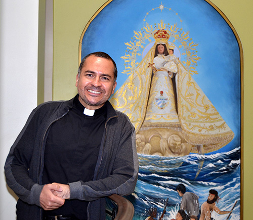Father Matias Hualpa in front of a mural of Our Lady of Charity, in the rectory at St. Thomas the Apostle Church, Miami.