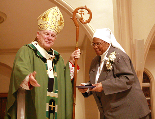 Sister Pierre Marie du Coeur de Jesus, marking 60 years with the Daughters of Wisdom, receives her gift of appreciation from Archbishop Thomas Wenski.